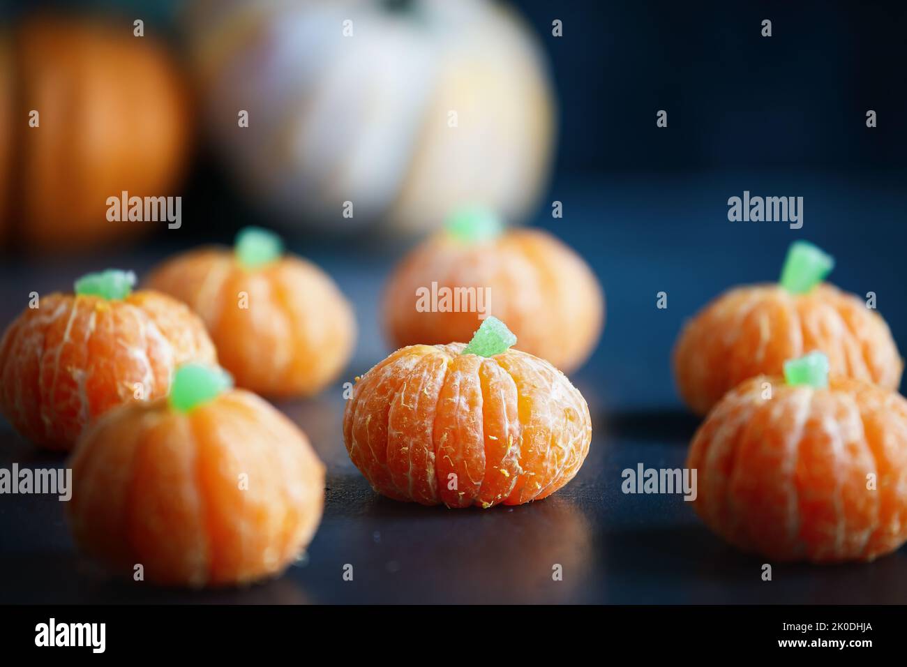 Halloween mignon citrouille orange fruit avec la tige de bonbons gélifiés. En-cas végétarien sain avec visages amusants pour la décoration de fête des enfants. Banque D'Images