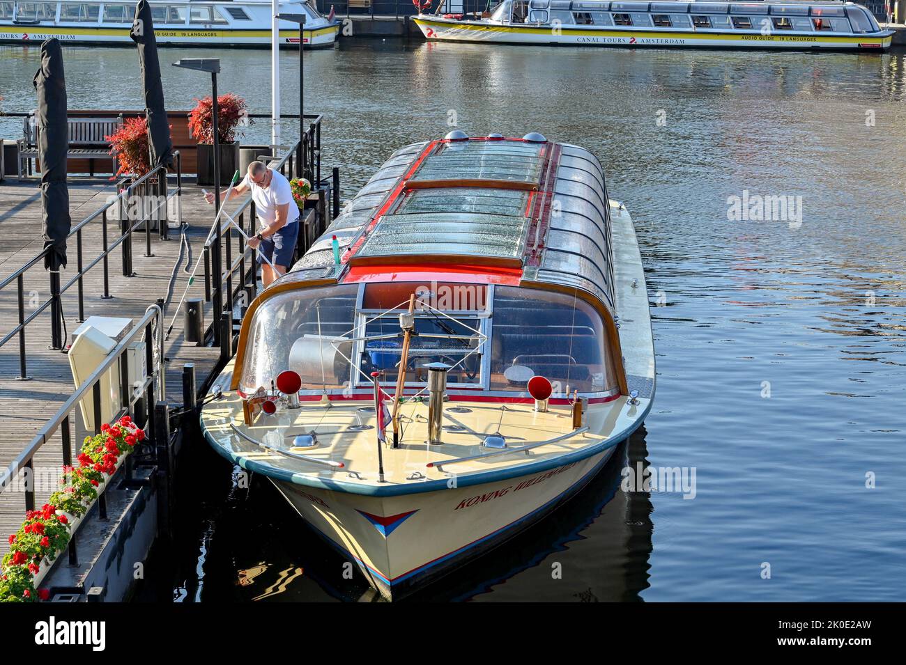 Amsterdam, pays-Bas - août 2022 : personne nettoyant la verrière d'un bateau touristique sur le canal à la lumière du matin Banque D'Images