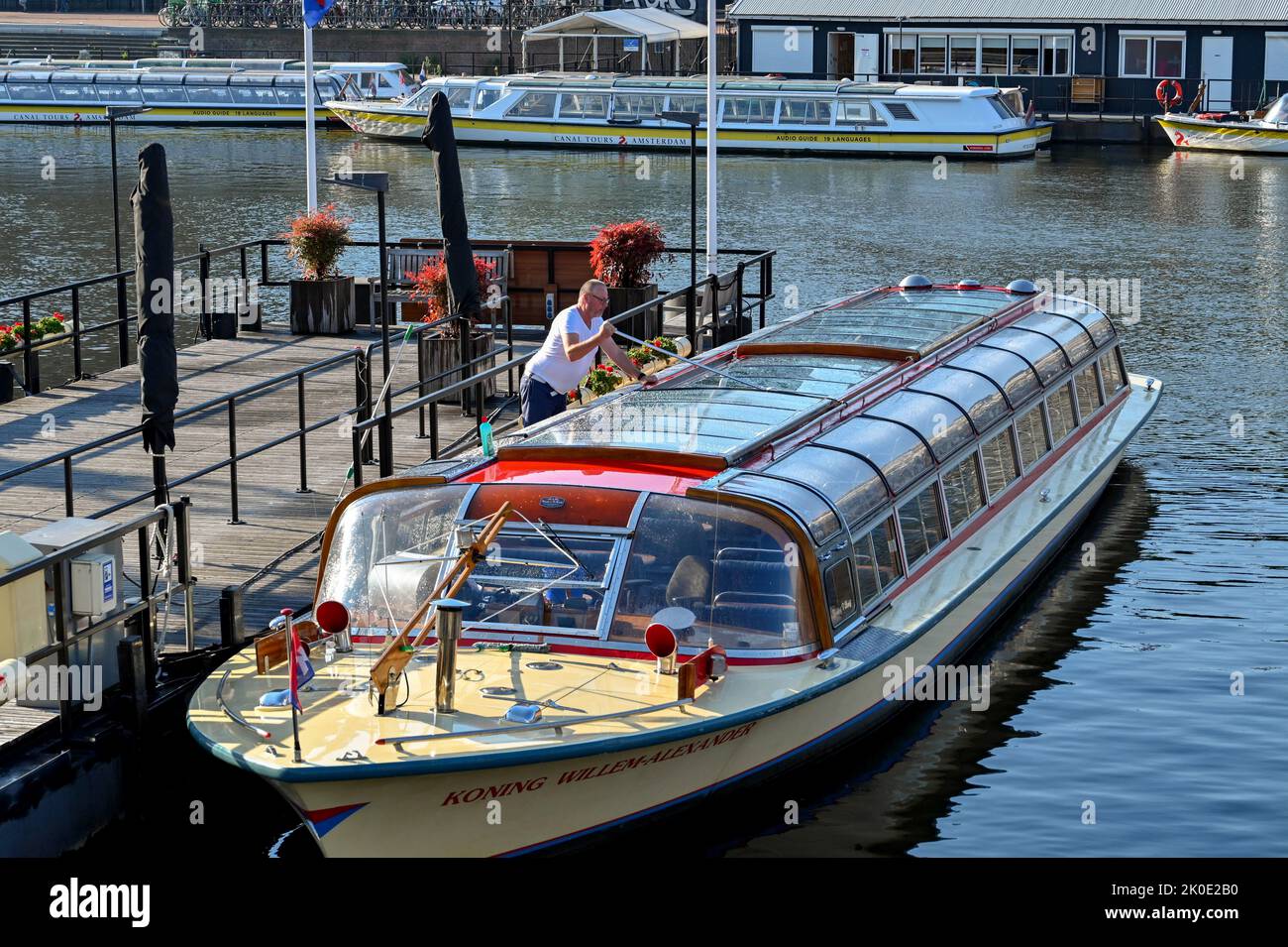 Amsterdam, pays-Bas - août 2022 : personne nettoyant la verrière d'un bateau touristique sur le canal à la lumière du matin Banque D'Images