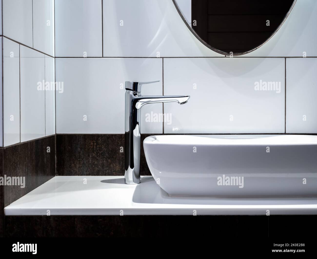 Robinet moderne en acier inoxydable sur lavabo en céramique blanche dans la salle de bains avec miroir. Nettoyer le lavabo en céramique de forme rectangulaire sur la décoration de comptoir en marbre Banque D'Images
