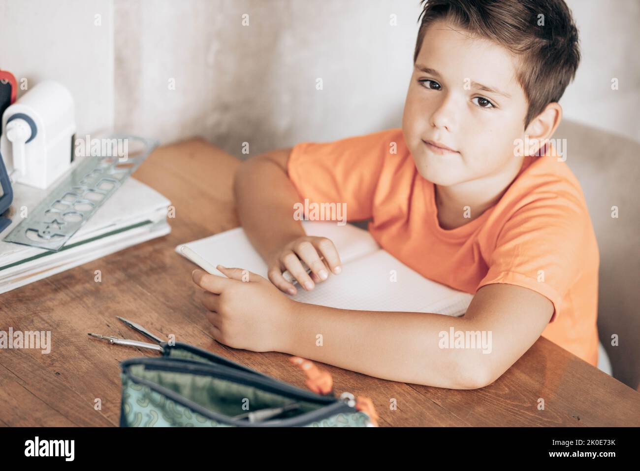 Petit garçon d'école faisant des devoirs, assis à la table Banque D'Images