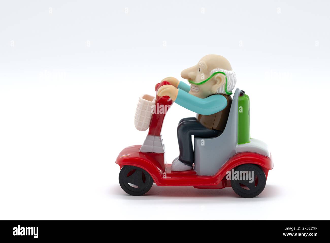 Grand-père sur fauteuil roulant motorisé, jouets, fond blanc, image rognée Banque D'Images
