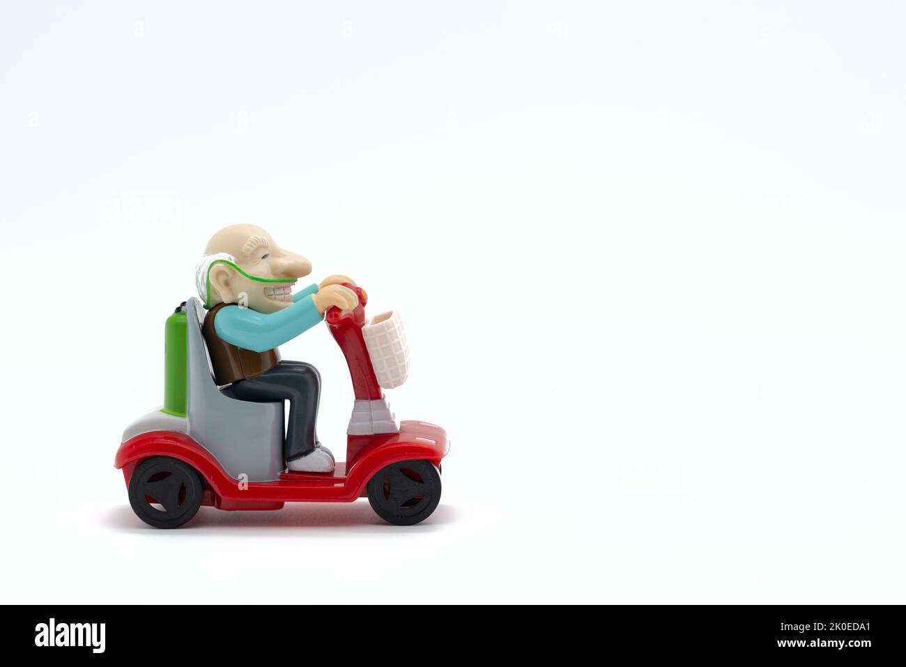 Grand-père sur fauteuil roulant motorisé, jouets, fond blanc, image rognée Banque D'Images