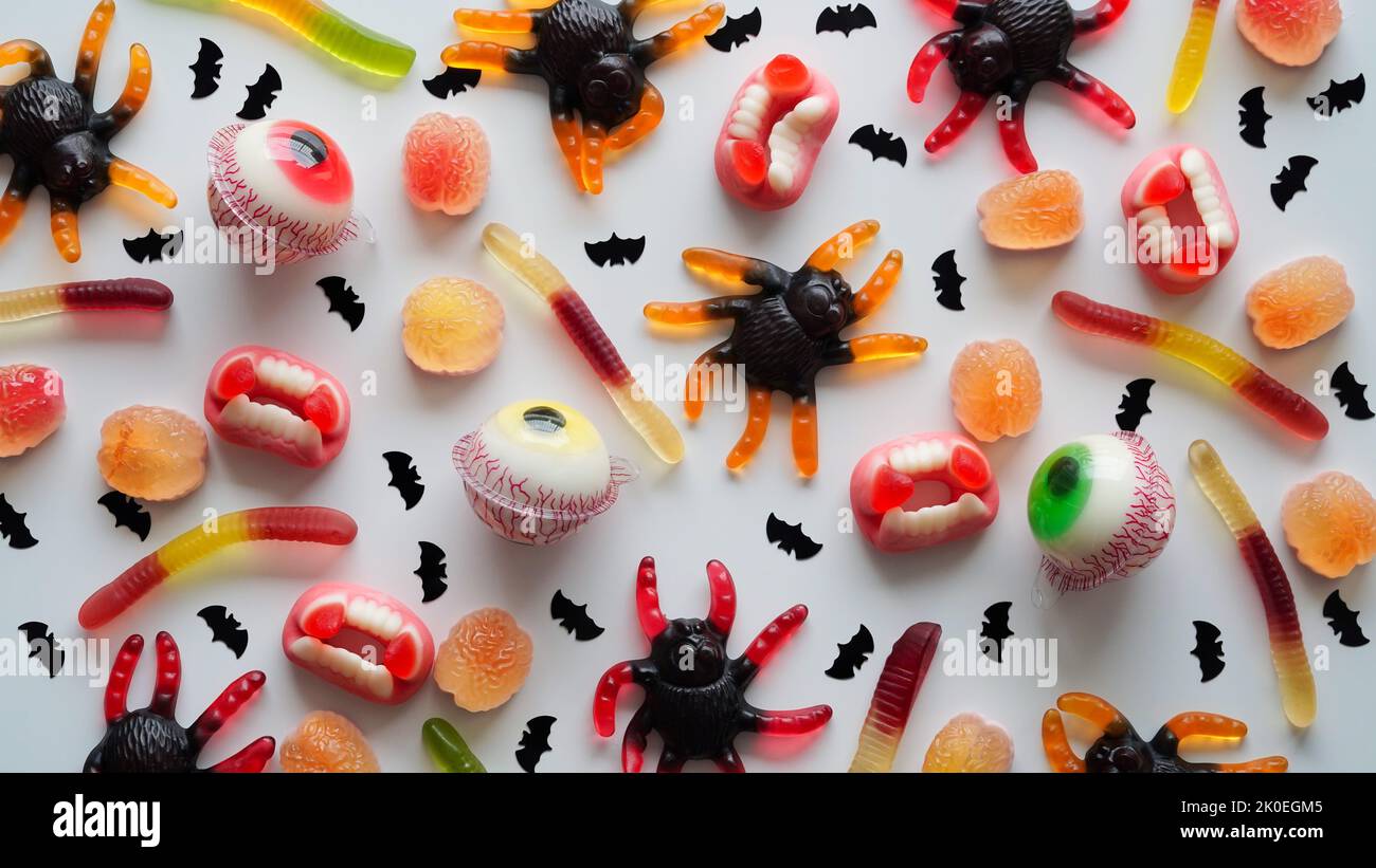 Gros plan de bonbons brillants en gelée, araignées, yeux, mâchoires, vers et chauves-souris, sur fond blanc, vue de dessus, plat, copier l'espace.décor concept pour Halloween partie, holi Banque D'Images