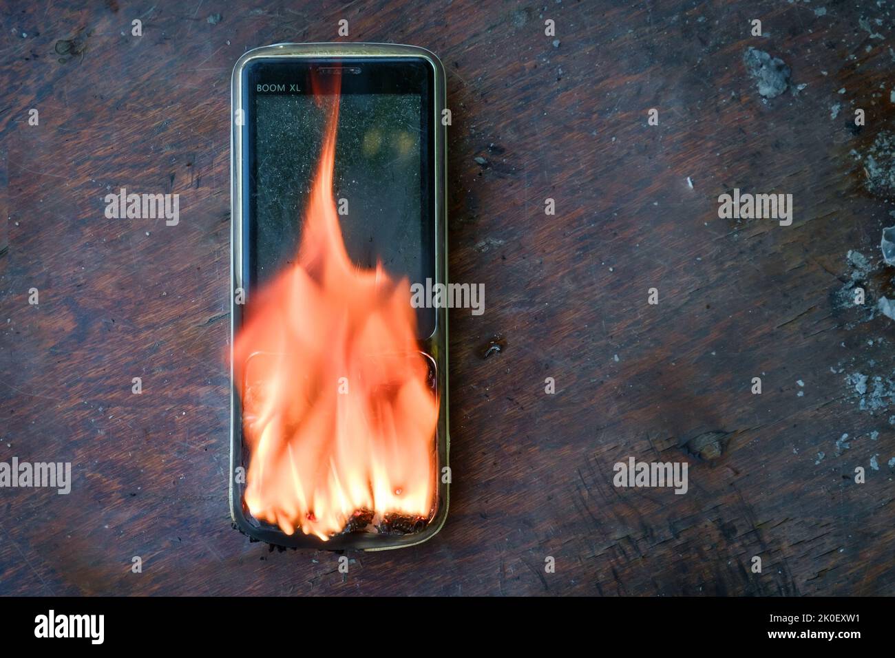 un téléphone noir se trouve sur la table et brûle avec une flamme vive Banque D'Images