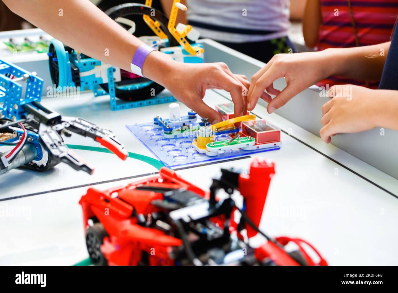 Défocus les mains des enfants tenant des robots prêts à l'emploi sur une table joyeuse et intelligente Whizzkid expérimentant avec une main robotique humanoïde tout en développant ses compétences. Banque D'Images