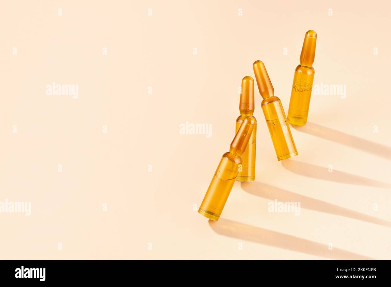 Ampoules cosmétiques avec sérum sur fond beige crème avec ombres et caustiques. Cheveux de beauté, rajeunissement et cosmétiques pour les soins de la peau. Banque D'Images