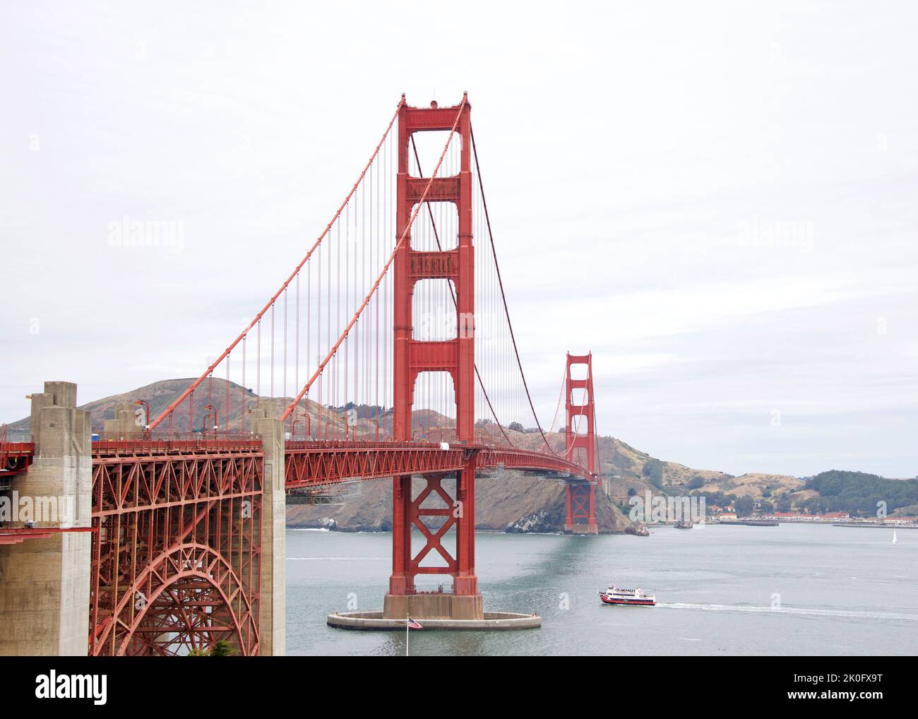 Golden Gate Bridge par temps clair, des nuages soufflent dans le ciel. Bateau rouge dans l'eau sous le pont. Banque D'Images