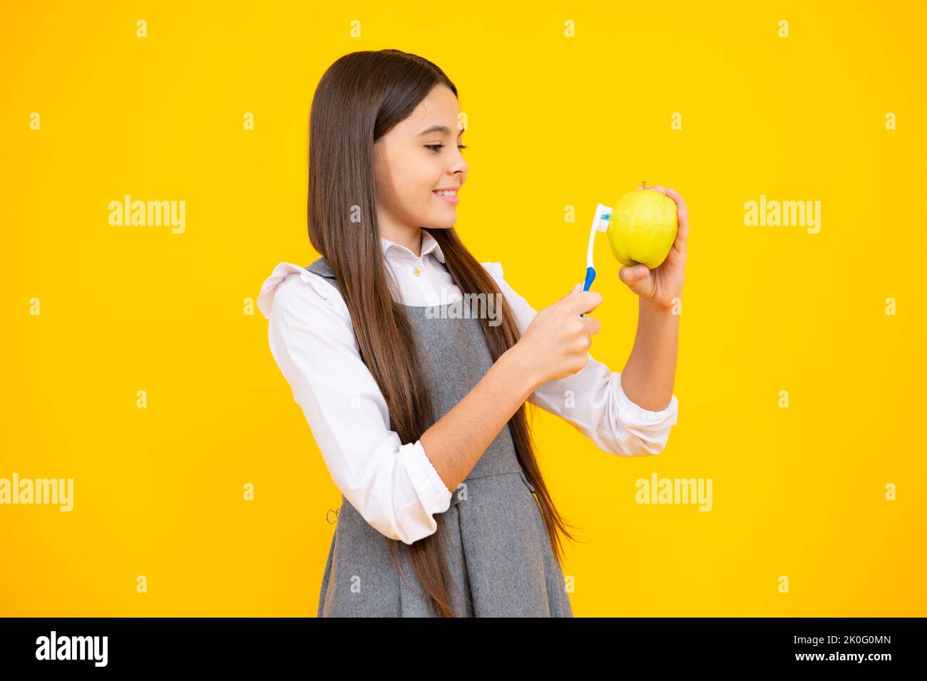 Vitamines de pomme pour des dents saines. Portrait de la jeune fille caucasienne tient une brosse à dents se brossant ses dents, routine du matin, hygiène dentaire, isolé dessus Banque D'Images