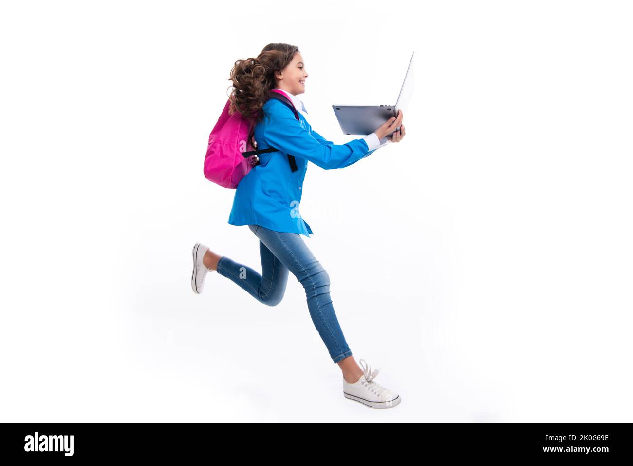 Retour à l'école. Adolescente tient un ordinateur portable. Les écoliers sur fond de studio blanc isolé. Courez et sautez, sautant un enfant. Banque D'Images