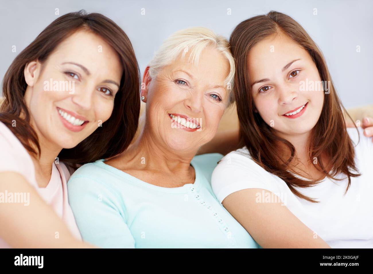 Beau portrait de la famille des filles. Trois générations de filles assises ensemble sur le canapé-salon ensemble souriant. Banque D'Images
