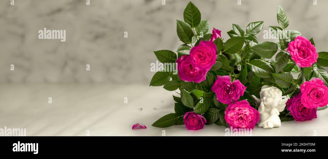 Bannière. Ange mignon avec un bouquet de roses roses sur un fond de marbre blanc. Le thème de l'amour. la saint-valentin. Une carte postale pour les vacances. Bonne Une Banque D'Images