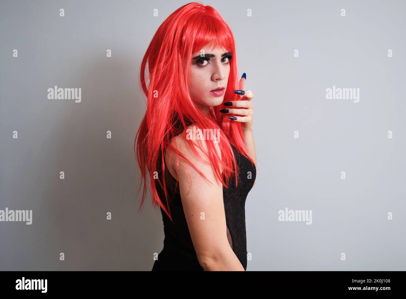 Portrait d'une reine de drag portant une perruque rouge et regardant l'appareil photo. Banque D'Images