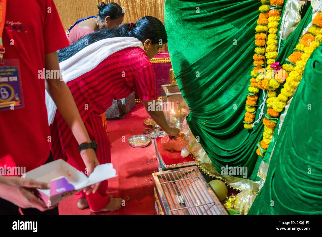 Une femme priant devant une belle idole de Lord Ganesha à un mandal à Mumbai pour le festival indien de Ganesh Chaturthi Banque D'Images
