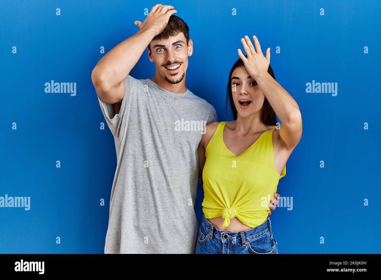Jeune couple hispanique debout ensemble sur fond bleu surpris par la main sur la tête pour l'erreur, se souvenir de l'erreur. oublié, mauvais concept de mémoire. Banque D'Images Jeune couple hispanique debout ensemble sur fond bleu surpris par la main sur la tête pour l'erreur, se souvenir de l'erreur. oublié, mauvais concept de mémoire. Banque D'Images