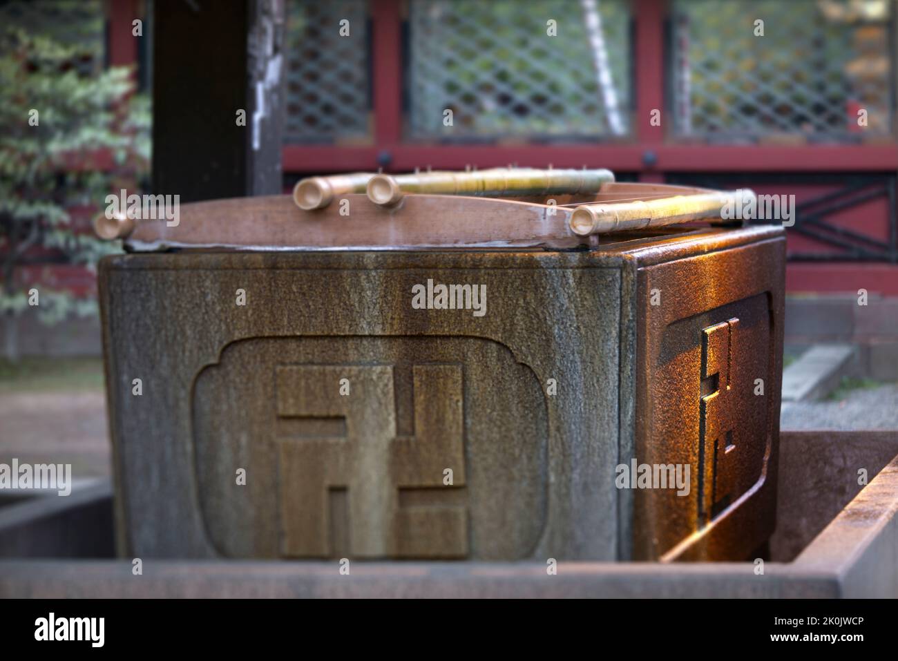 Pierre de pavillon d'ablution de temizuya ou de chozuya traditionnelle japonaise utilisée pour le rituel de purification de shinto orné d'une croix bouddhiste sculptée. Banque D'Images