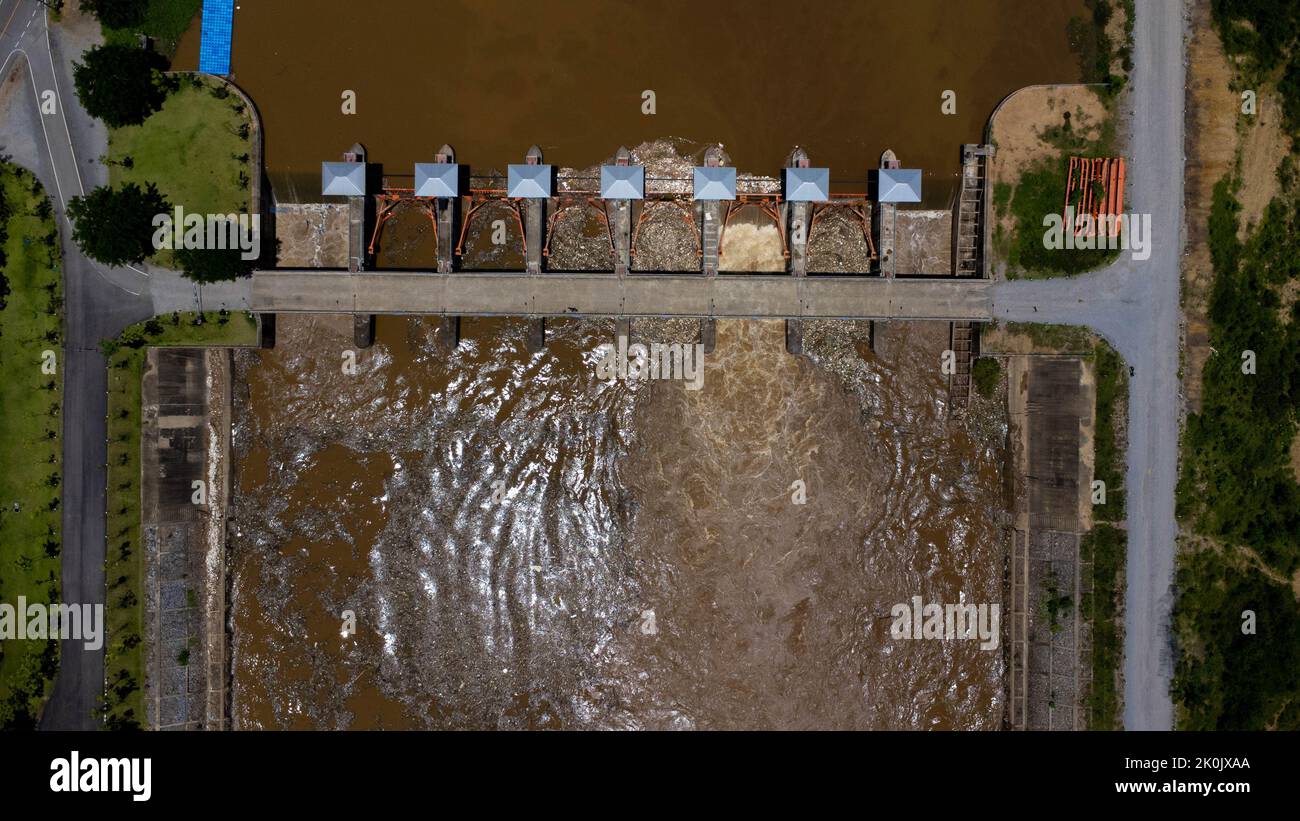 Vue aérienne de l'eau libérée par le canal de drainage du barrage en béton comme débordement dans la saison des pluies. Vue de dessus de l'eau de forêt brun trouble Banque D'Images