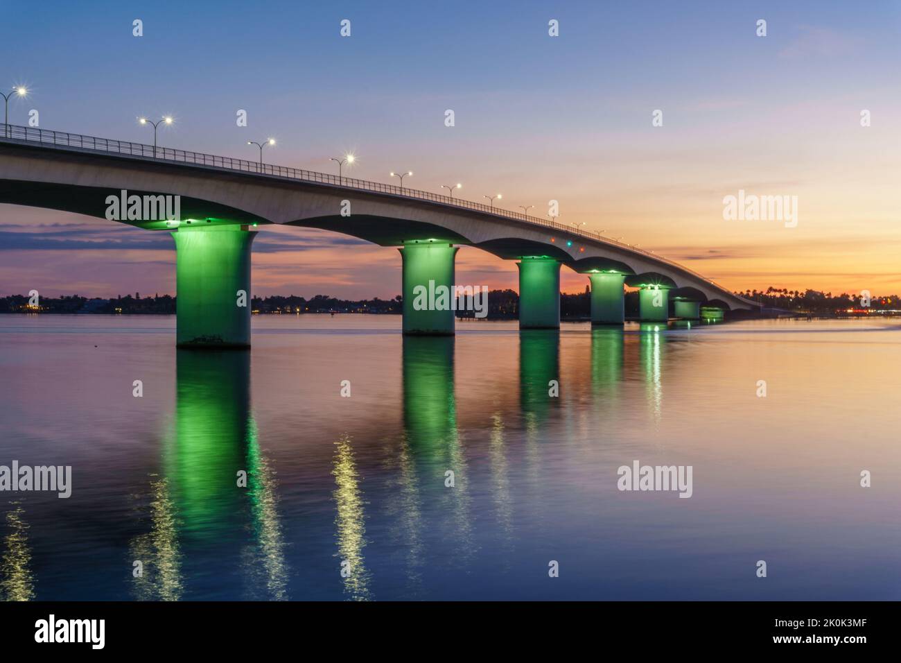 Pont de Ringling à Sarasota, Floride au coucher du soleil avec des fermes éclairées de vert. Banque D'Images