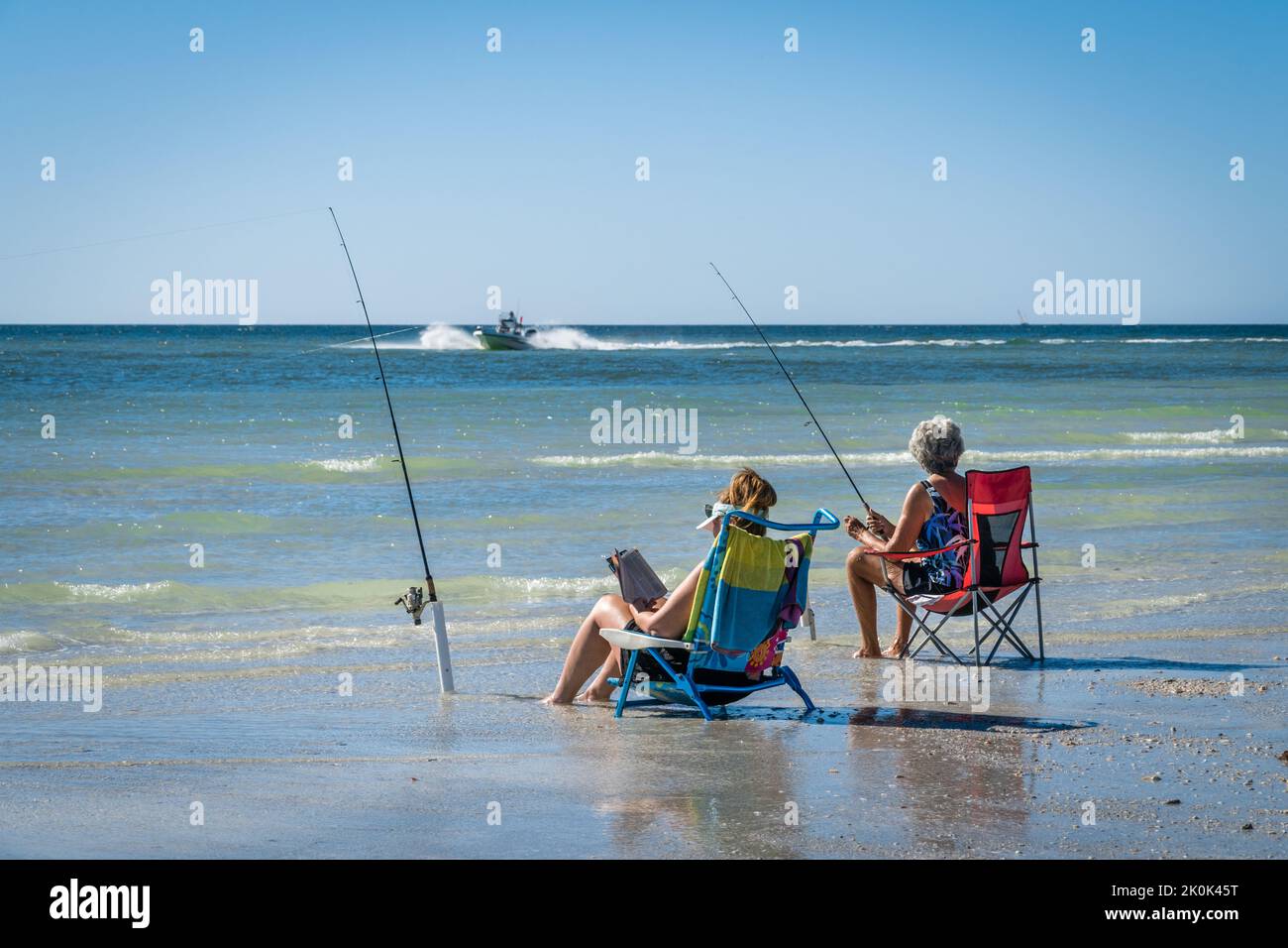 Sarasota, FL, US-23 novembre 2020: Deux femmes pêchant sur la plage tropicale avec bateau à moteur en arrière-plan. Banque D'Images