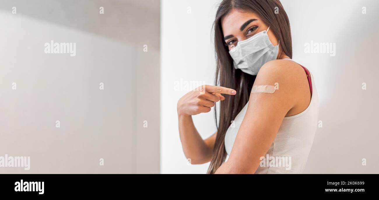 Jeune femme attentive, pointant vers une zone d'épaule, pendant une pandémie. Banque D'Images