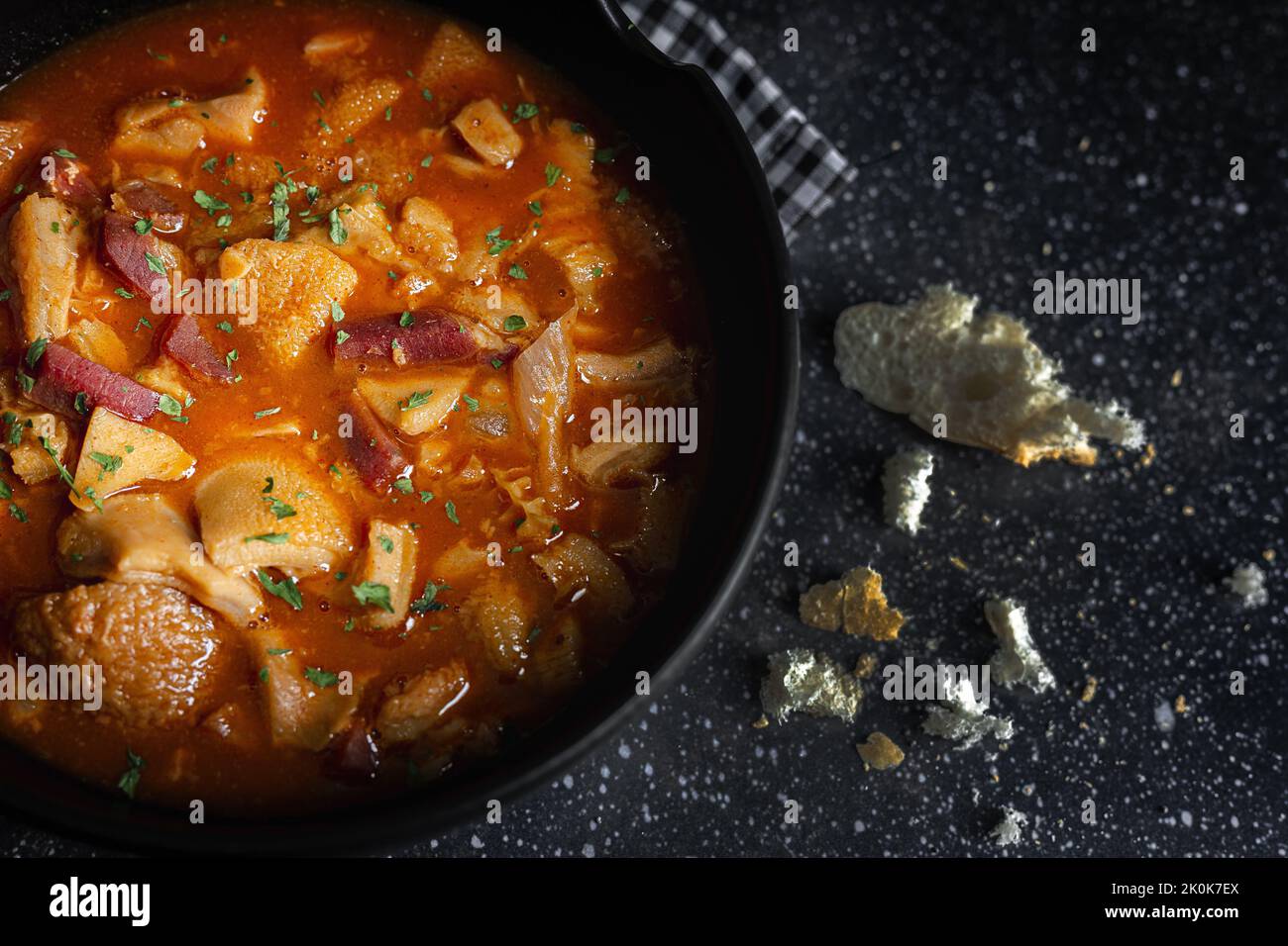 De dessus de savoureux callos a la madrilena dans un bol noir sur la table avec serviette Banque D'Images