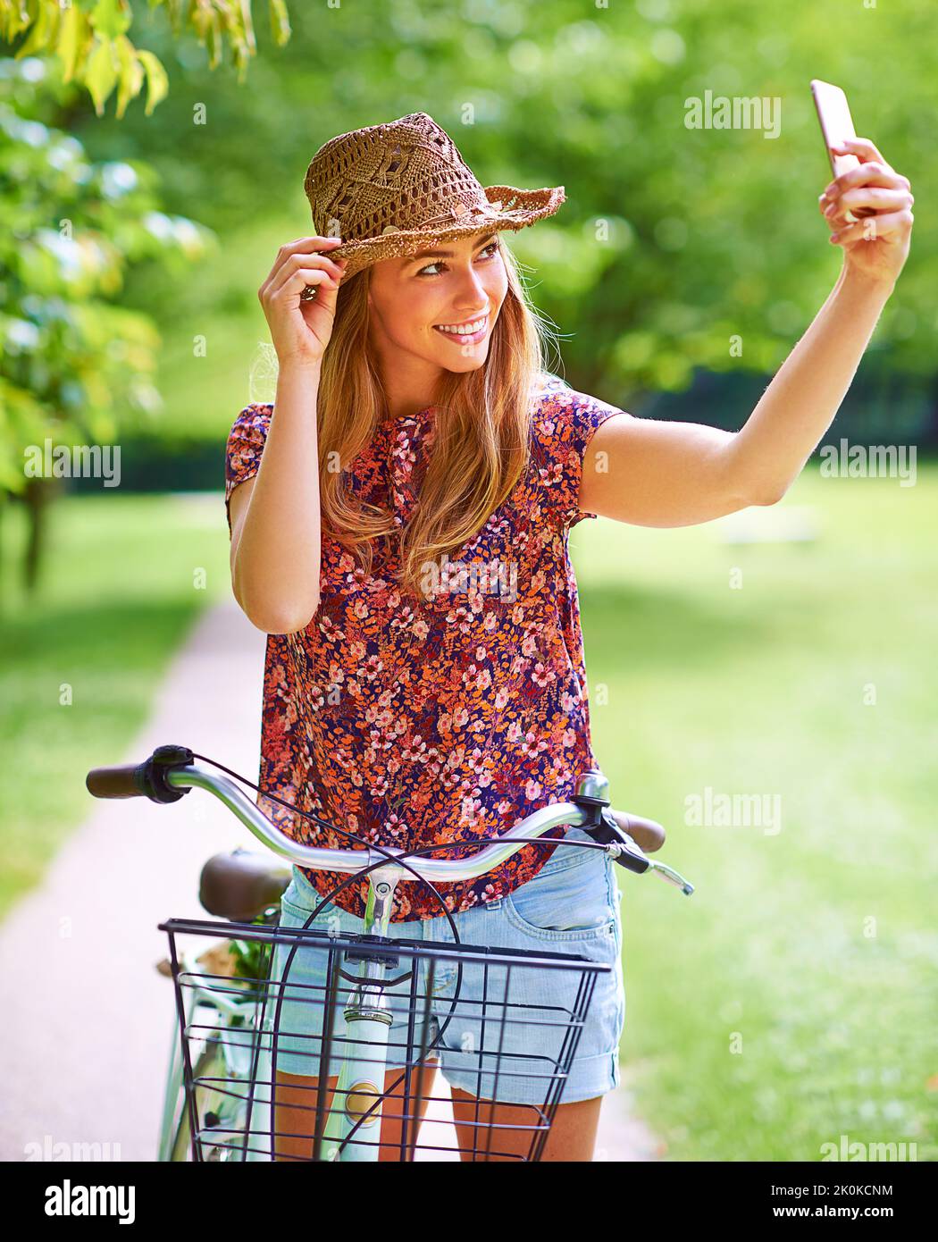 Ne laissez rien derrière vous dans la nature, mais des souvenirs. Une jeune femme qui prend un selfie tout en étant dehors pour une balade en vélo dans le parc. Banque D'Images