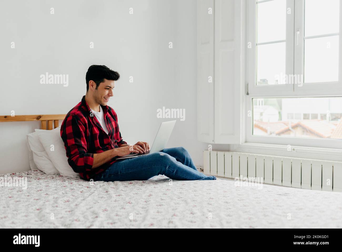 Vue latérale du beau caucasien qui travaille sur l'ordinateur portable dans la chambre à la maison Banque D'Images