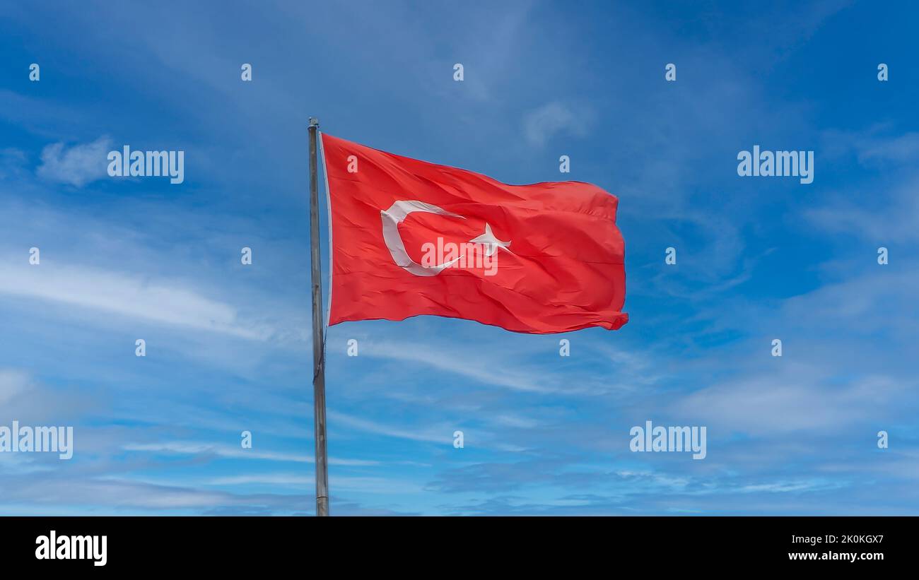 Drapeau turc agitant dans un ciel bleu ciel nuageux. Banque D'Images