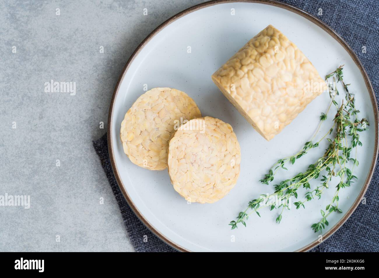 Vue de dessus tempeh ou tempeh cru, fait de graines de soja fermentées. Tranches de tempeh sur l'assiette avec des herbes. Protéines de soja. Concept de viande à base de plantes. Coo sain Banque D'Images Vue de dessus tempeh ou tempeh cru, fait de graines de soja fermentées. Tranches de tempeh sur l'assiette avec des herbes. Protéines de soja. Concept de viande à base de plantes. Coo sain Banque D'Images