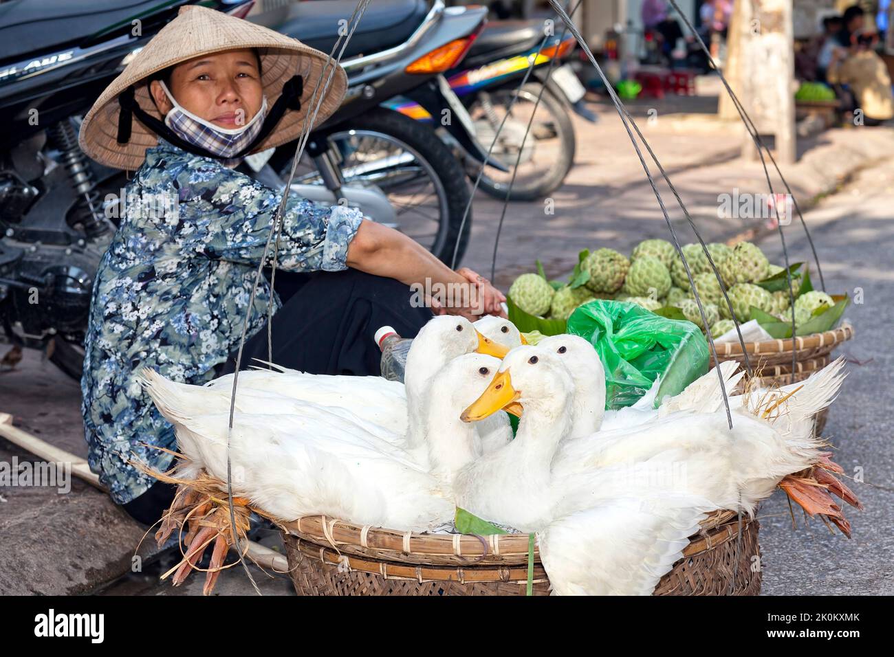 Vendeur vietnamien portant chapeau de bambou travaillant dans le marché de rue en plein air, Hai Phong, Vietnam Banque D'Images