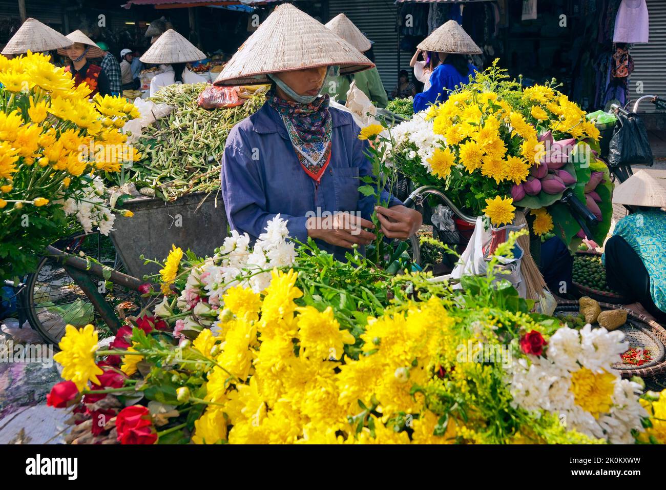 Vendeur vietnamien portant chapeau de bambou travaillant dans le marché de rue en plein air, Hai Phong, Vietnam Banque D'Images