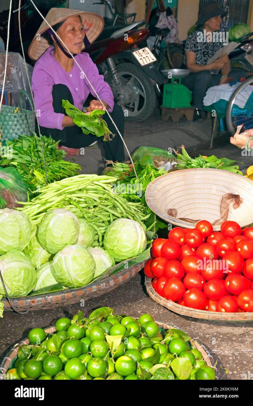 Vendeur vietnamien portant chapeau de bambou travaillant dans le marché de rue en plein air, Hai Phong, Vietnam Banque D'Images