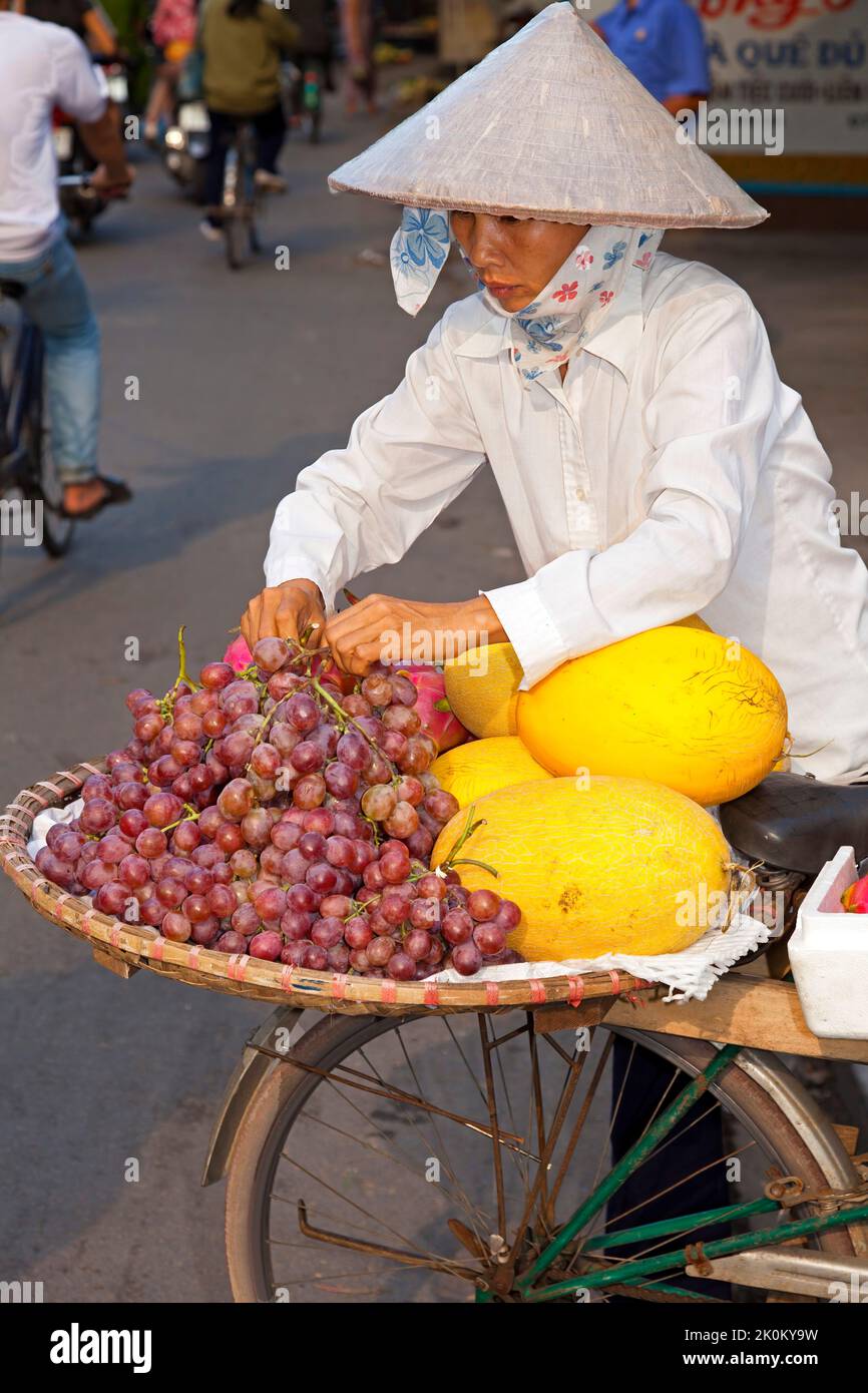 Vendeur vietnamien portant chapeau de bambou travaillant dans le marché de rue en plein air, Hai Phong, Vietnam Banque D'Images