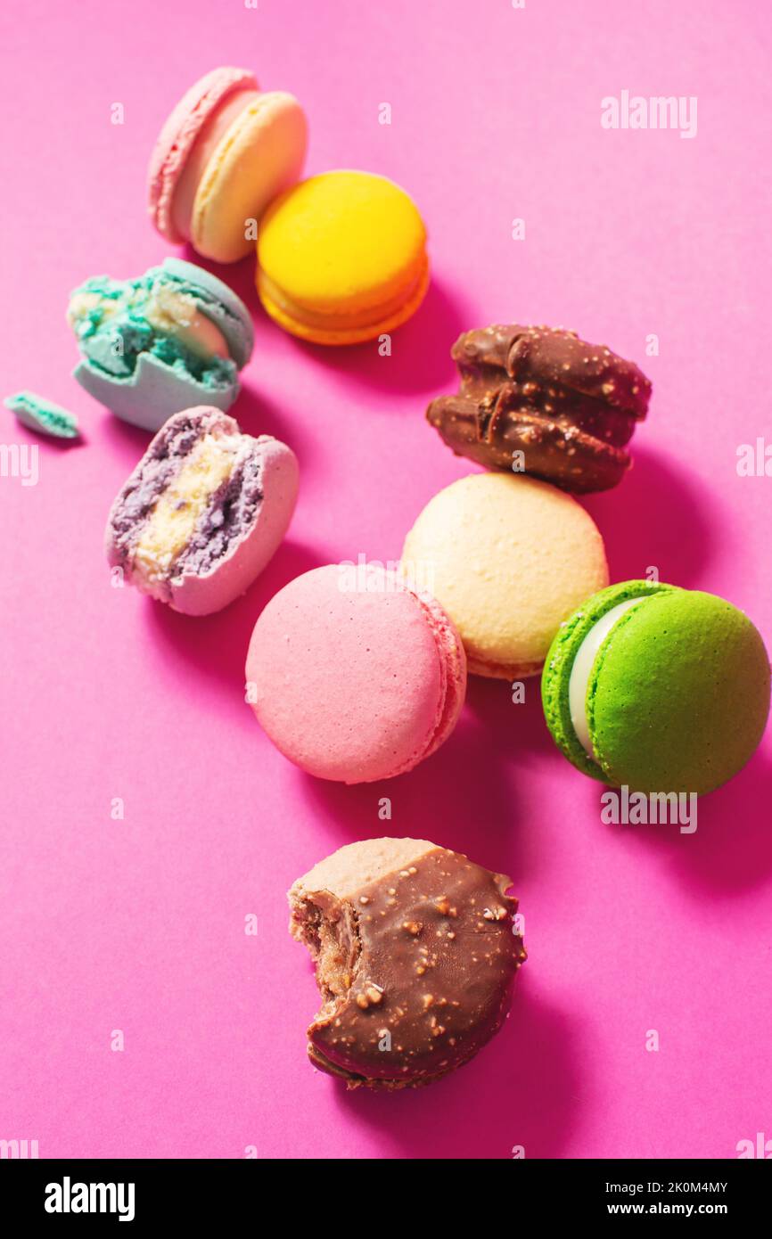 Des macarons colorés aux saveurs variées et aux couleurs vives, des biscuits sucrés sur fond rose coloré. Banque D'Images