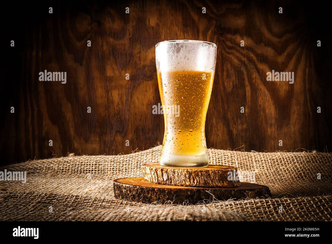 Verre avec bière et mousse sur fond de bois sombre Banque D'Images