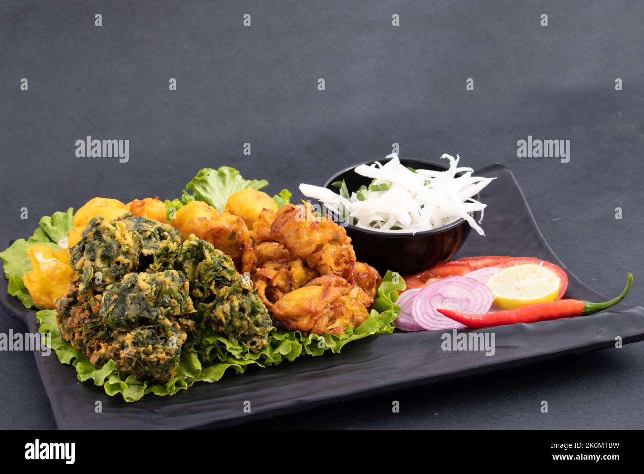 Les beignets indiens d'épinard et d'oignon Pakoda également appelés Pyaz Ke Pakore, Kanda Bhajji, Pyaaz Bajji, Pyaaz Bhaji ou Pyaaj Pakora est Deep Fried Street Banque D'Images