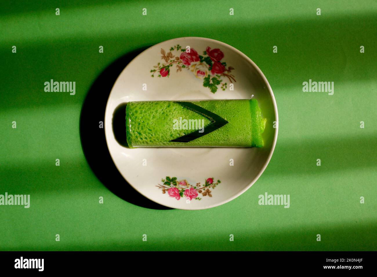 Rouleaux de crêpes de Pandan remplis de noix de coco dans une assiette. La nourriture traditionnelle indonésienne ou malayasienne appelée dadar gulung. Banque D'Images