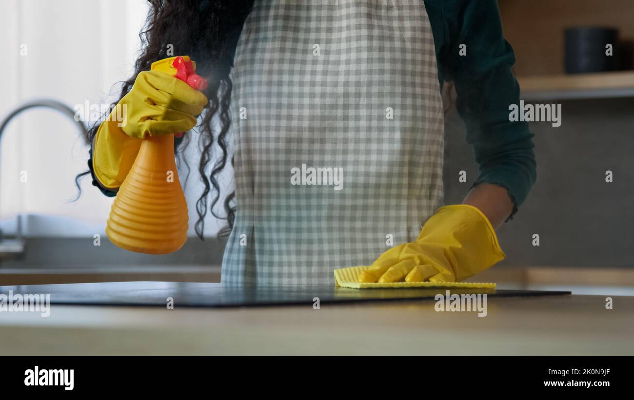Gros plan inconnu femme maman femme ménage lave-linge électrique poêle en caoutchouc jaune gants de nettoyage cuisine par chiffon humide gardant la maison propre poli Banque D'Images