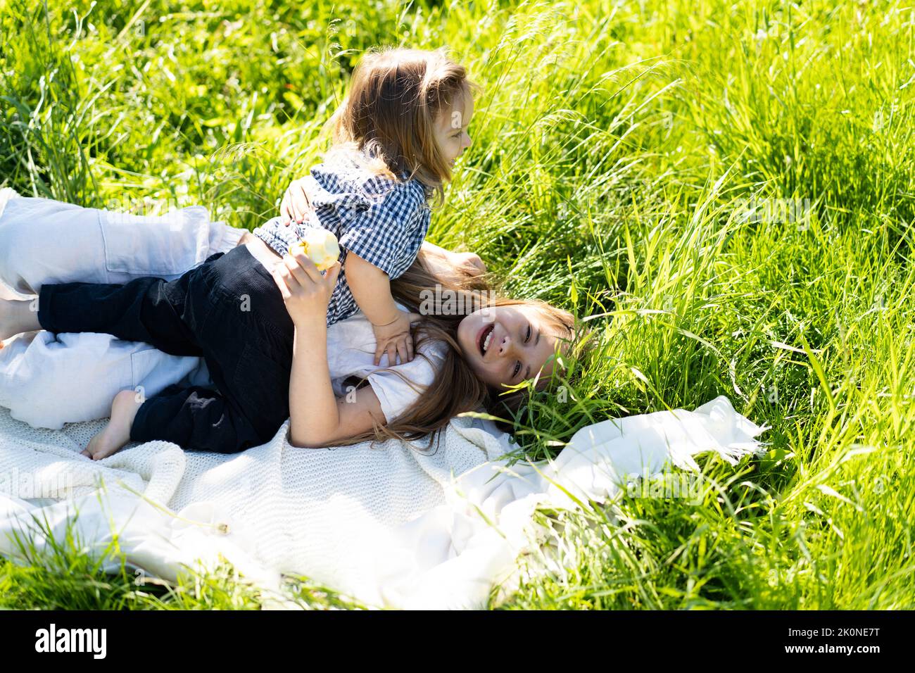 Frère et sœur se réjouîssent de rire, allongé sur l'herbe verte. Le soleil brille, les enfants sont heureux insouciant. Le concept d'une vie de famille heureuse et de liaison. Copier l'espace. Banque D'Images