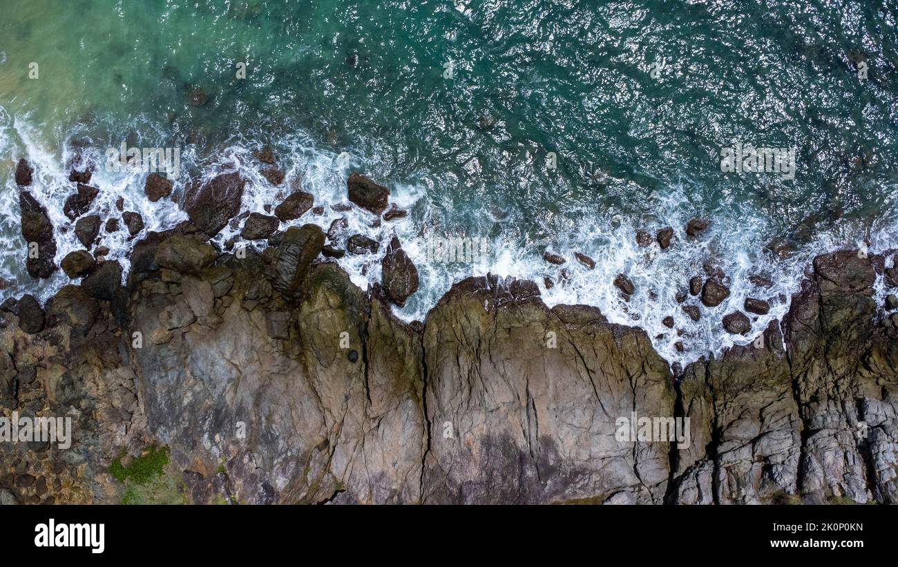 Vue aérienne des vagues de mer s'écrasant sur les rochers de la falaise dans l'océan bleu. Vue sur les rochers côtiers de l'océan de Phuket. Point de vue sur le paysage de Laem Phromthep Banque D'Images