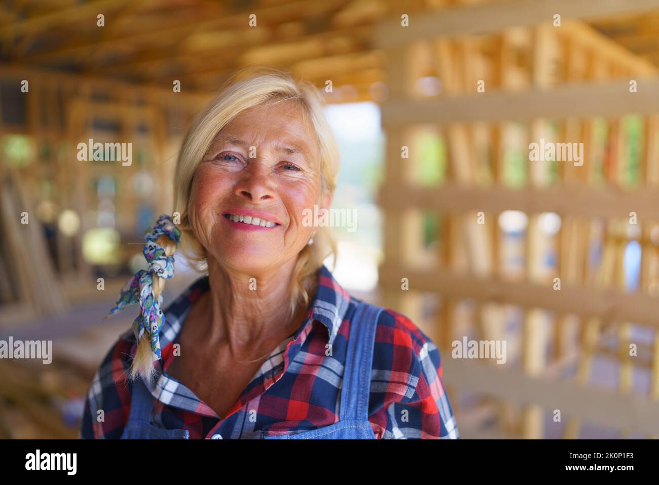 Portrait de la femme heureuse senior manuel travaillant à l'intérieur de son inachevé écologique durable en bois éco-maison. Concept de femmes actives indépendantes Banque D'Images