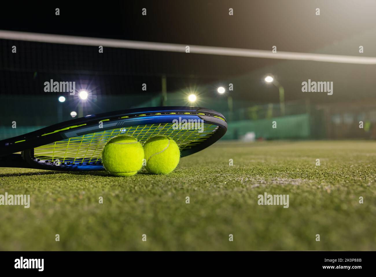 jouez au tennis dans l'obscurité grâce à un éclairage artificiel. raquette et balles sur un court extérieur avec espace pour copier Banque D'Images