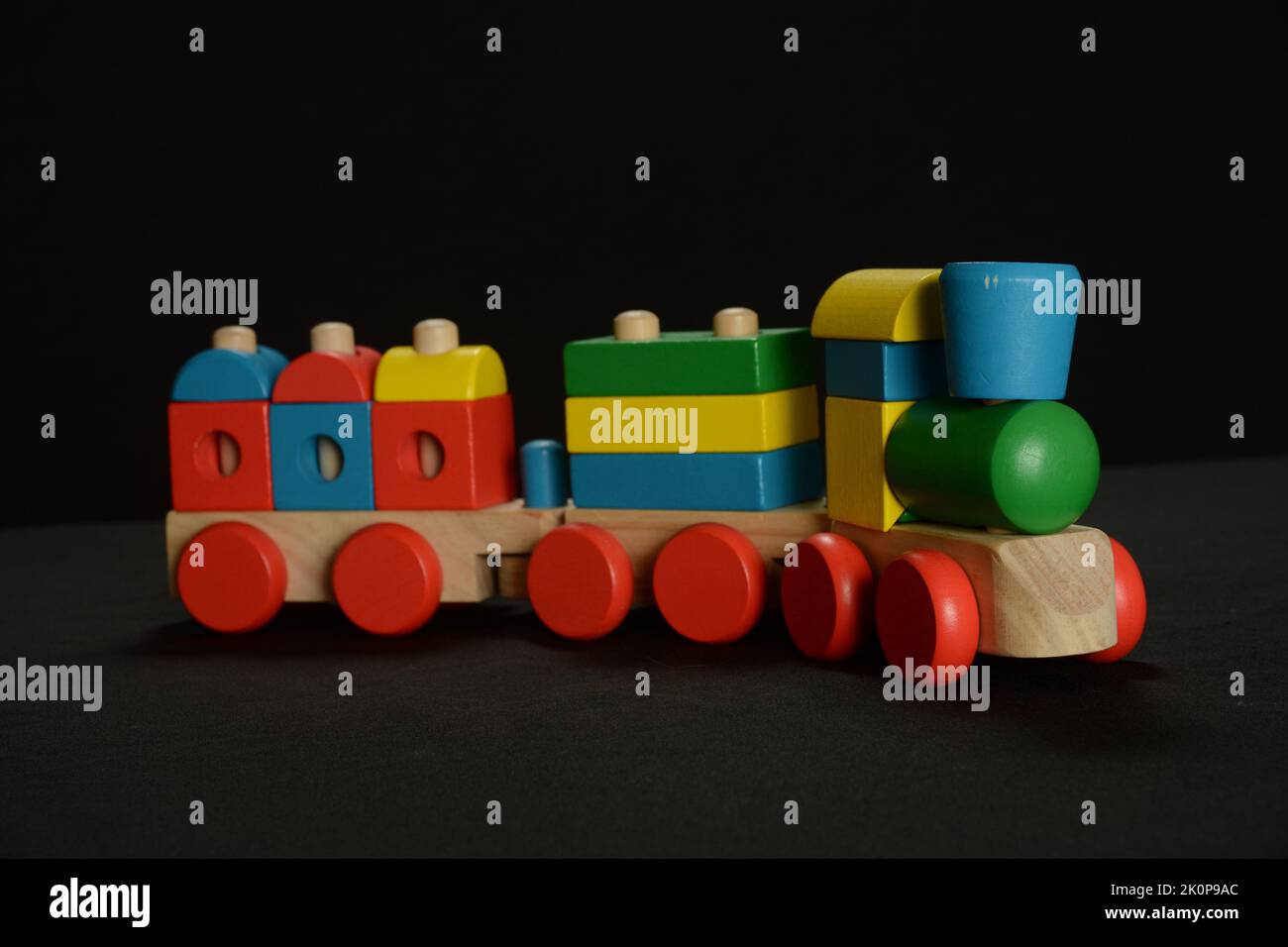 Un jouet de train en bois coloré sur fond noir Banque D'Images