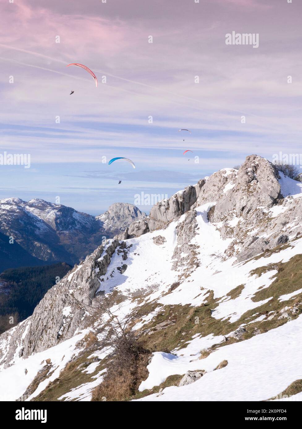 des parapentes planant sur les montagnes en hiver au coucher du soleil Banque D'Images