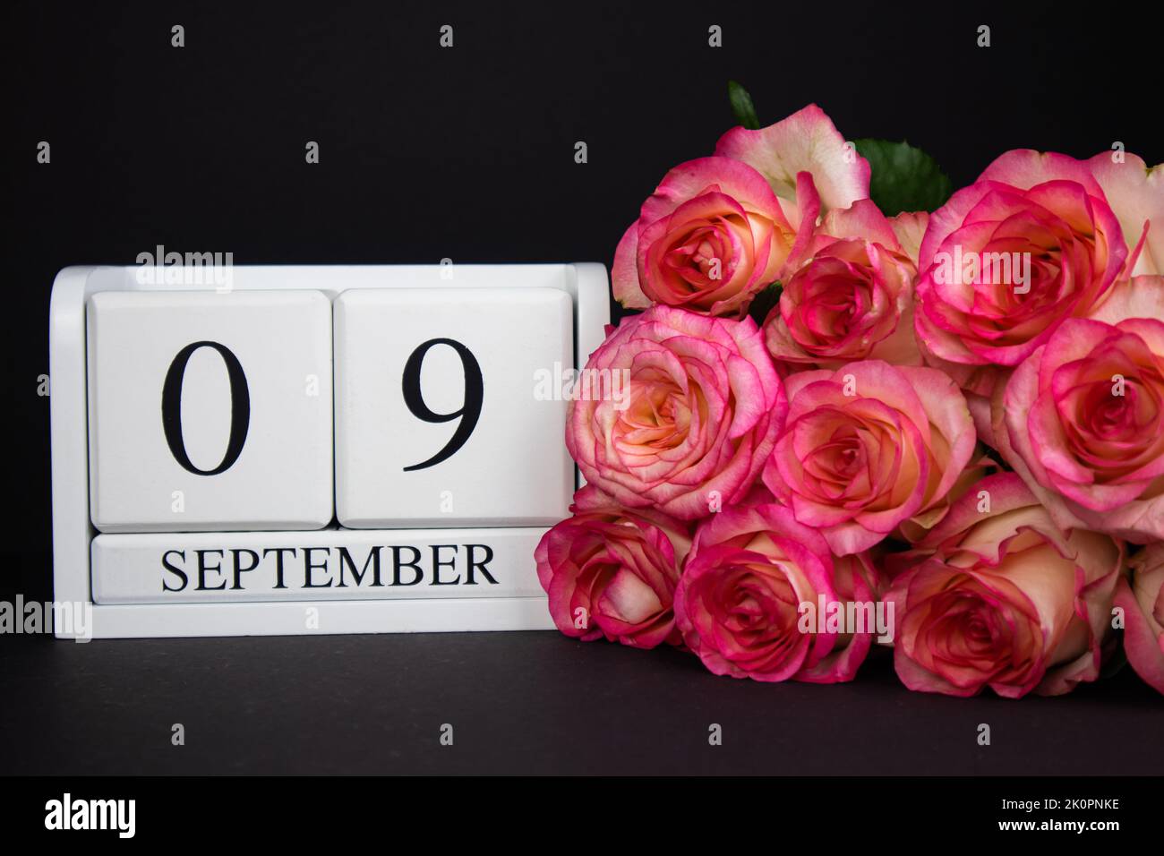 9 septembre calendrier en bois, blanc sur fond noir, roses se trouvent à proximité. Banque D'Images