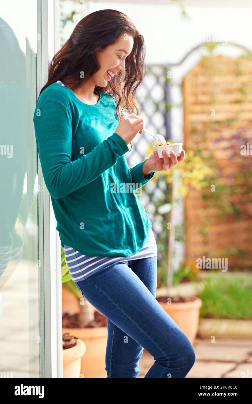 Une journée extraordinaire commence par un petit déjeuner extraordinaire. Une jeune femme mange un en-cas sain à la maison. Banque D'Images