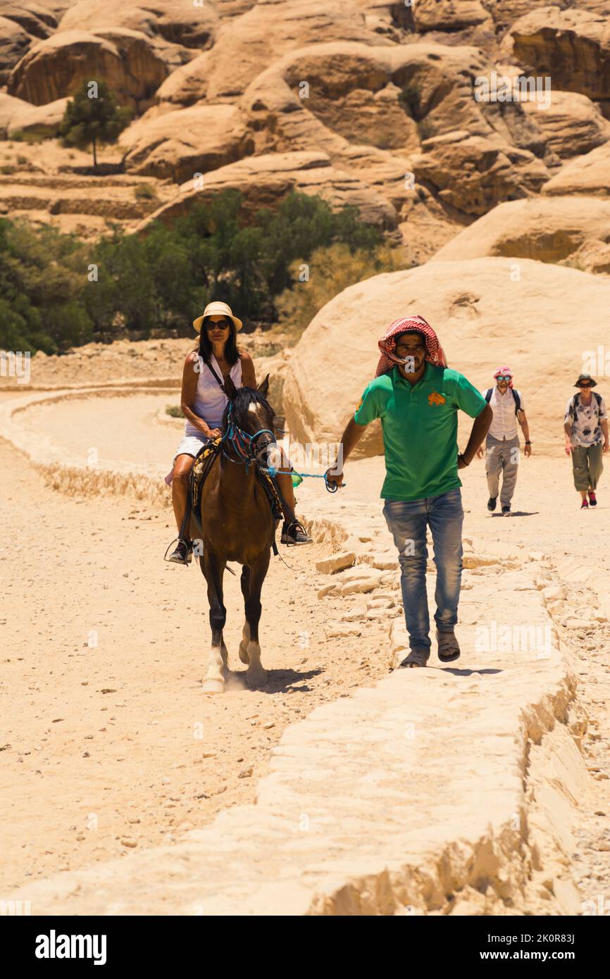 06.18.2022. Petra Canyon, Jordanie. Un homme local qui mène un cheval avec un touriste. Photo de haute qualité Banque D'Images
