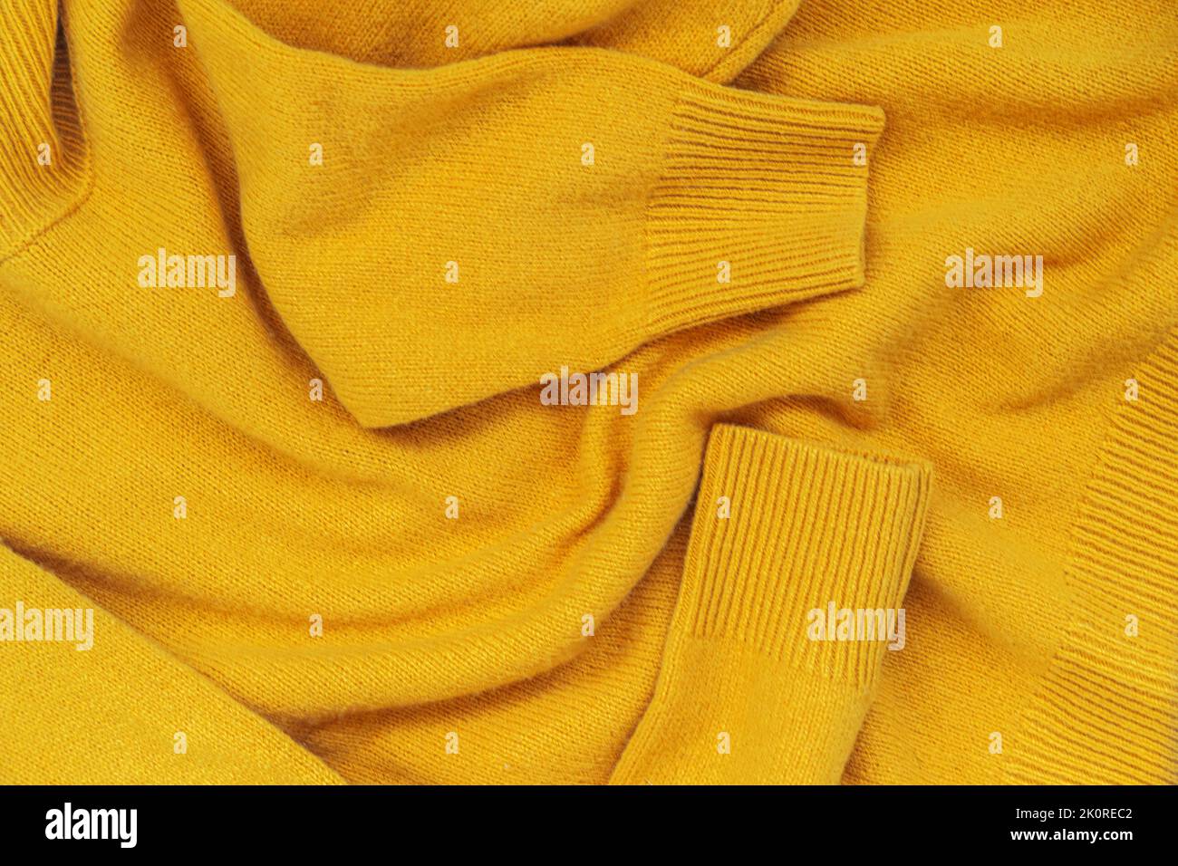 Pull en laine jaune tricoté, pose plate, arrière-plan. Collection de vêtements d'automne faits maison Banque D'Images