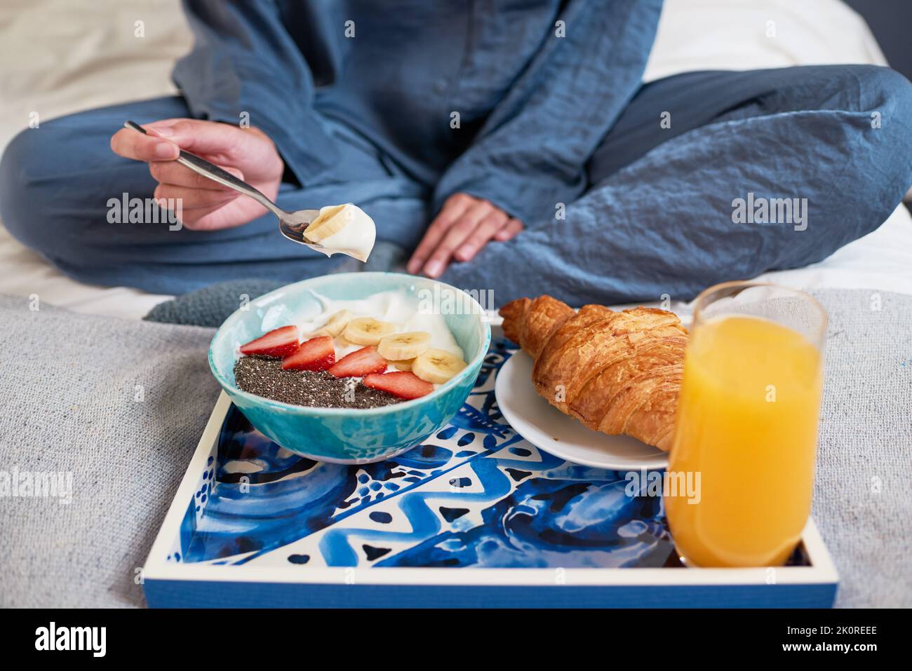 Gros plan de la jeune femme mangeant un bol de petit déjeuner au lit en pyjama Banque D'Images