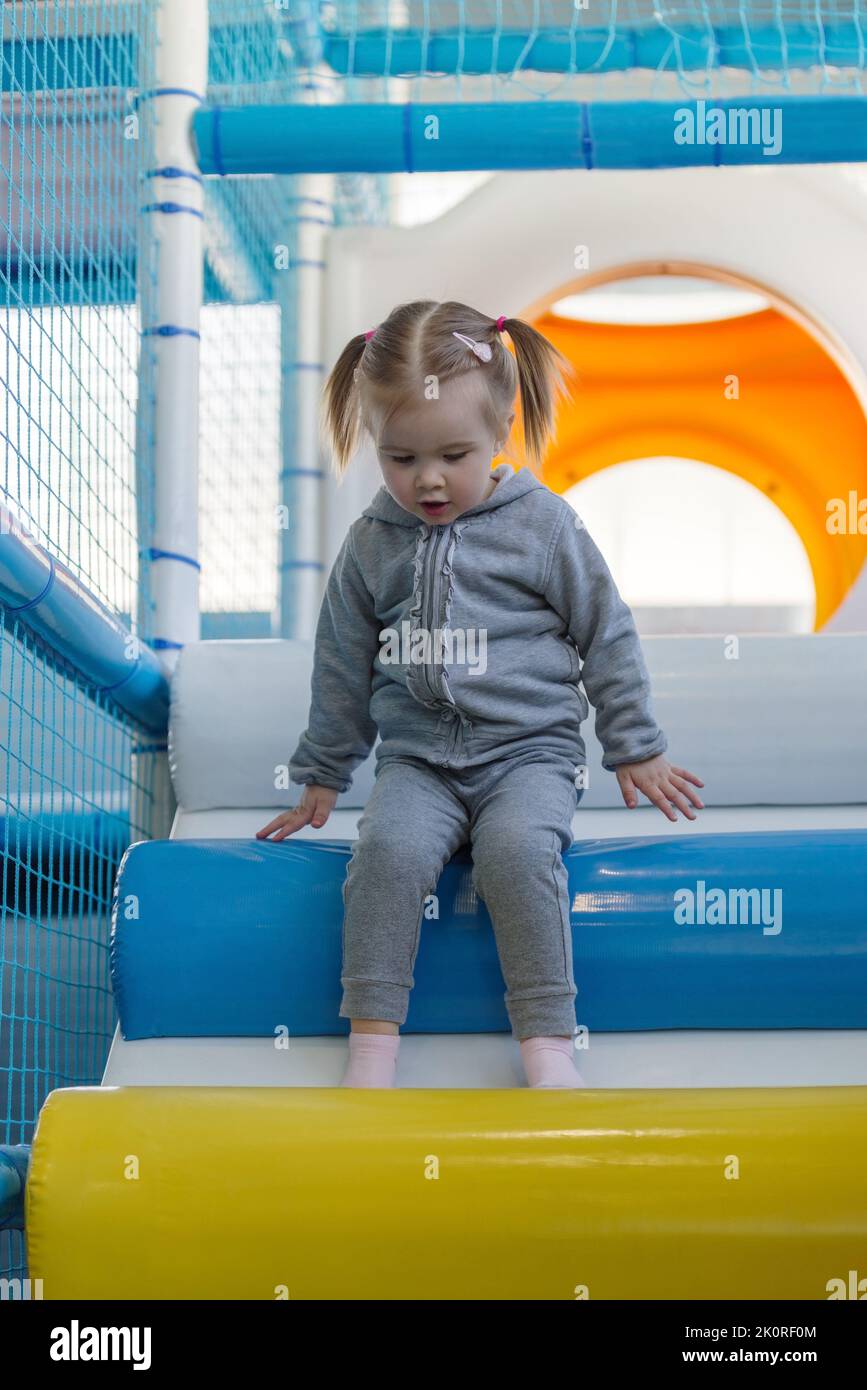 Enfant fille grimpant sur la rampe dans le centre de jeu mou Banque D'Images